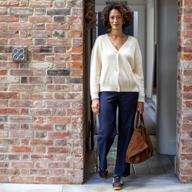 Woman standing in a doorway with a brick wall and door frame.