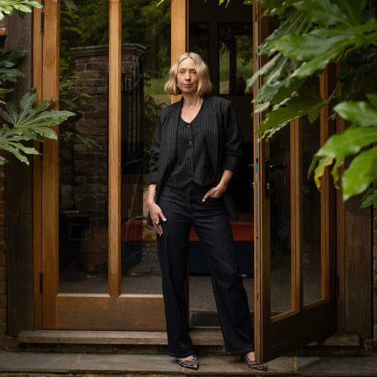Woman standing in a doorway with greenery on either side