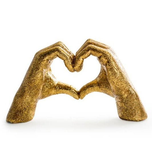 Gold sculpture of two hands forming a heart shape on a white background